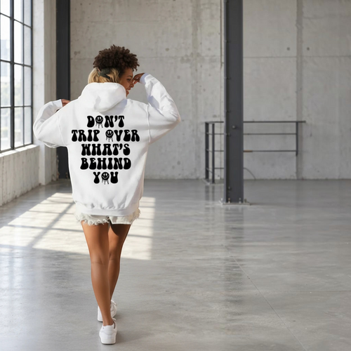 BY JAXXIE witte oversized hoodie met zwarte Don't Trip backprint gedragen door een vrouw in een industriële ruimte